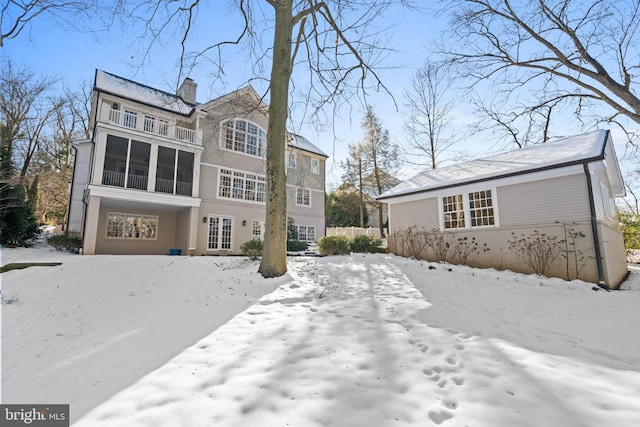 snow covered back of property with a balcony