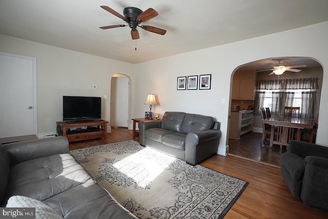 living room with dark wood-type flooring, ceiling fan, and a baseboard heating unit