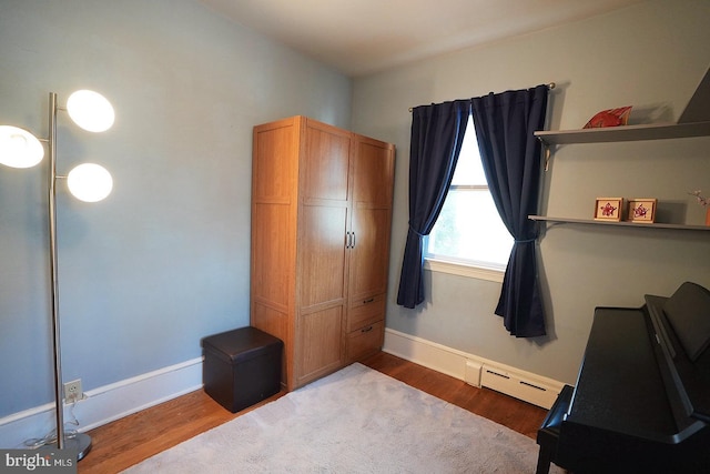 bedroom featuring a baseboard heating unit and hardwood / wood-style floors