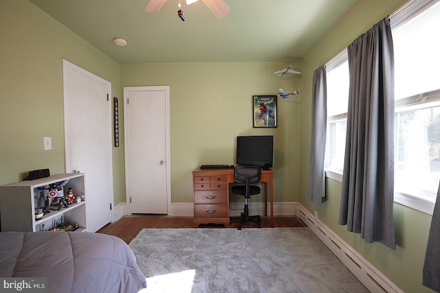 bedroom with hardwood / wood-style floors, a baseboard radiator, and ceiling fan