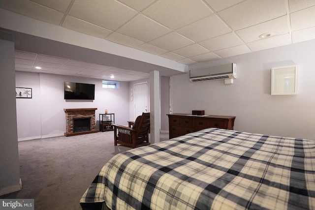 carpeted bedroom with a stone fireplace, a paneled ceiling, and a wall mounted AC