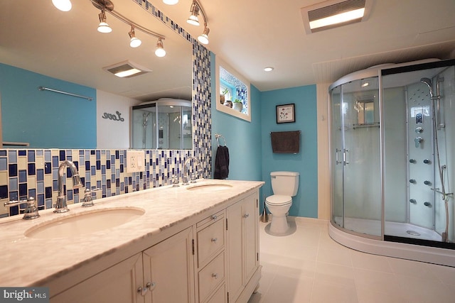 bathroom with tile patterned floors, toilet, tasteful backsplash, vanity, and a shower with door