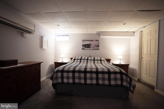 bedroom with an AC wall unit, a drop ceiling, and dark colored carpet