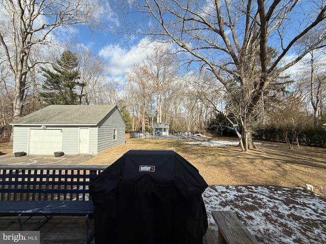 yard layered in snow featuring a garage and an outbuilding