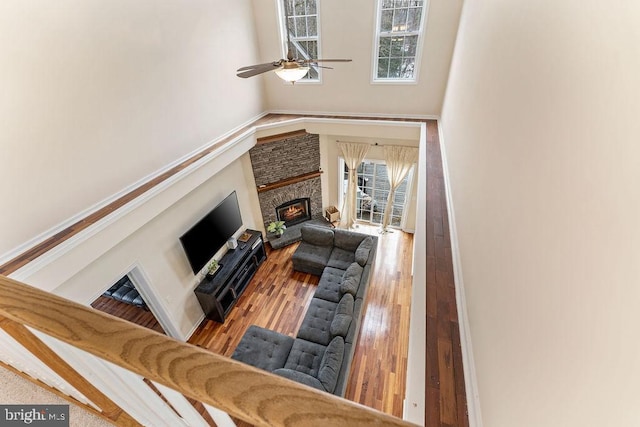 living room with ceiling fan, wood-type flooring, a healthy amount of sunlight, and a fireplace