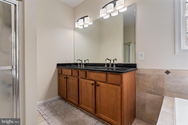 full bathroom with a stall shower, double vanity, and a sink