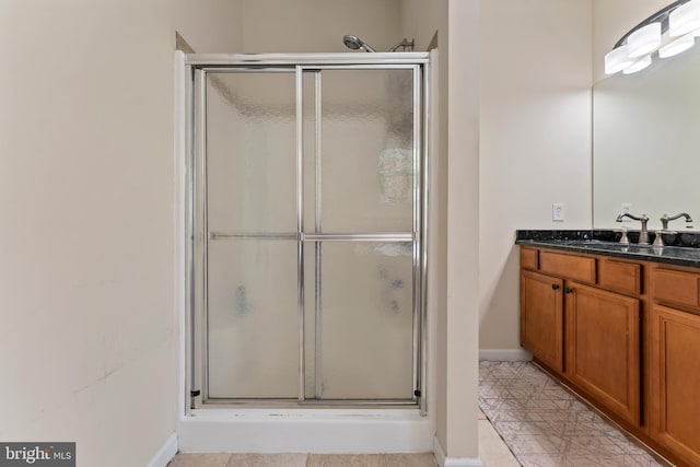 full bathroom featuring baseboards, a shower stall, and vanity