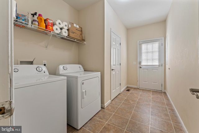 laundry room with baseboards, light tile patterned floors, laundry area, and washing machine and clothes dryer