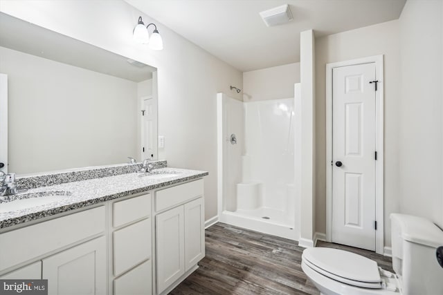 bathroom with toilet, hardwood / wood-style flooring, walk in shower, and vanity