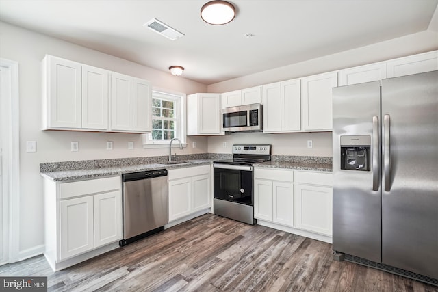 kitchen featuring stainless steel appliances, white cabinets, sink, and hardwood / wood-style flooring