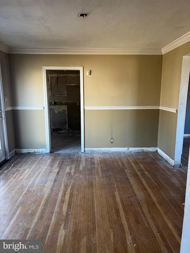 empty room featuring a textured ceiling, hardwood / wood-style floors, and ornamental molding