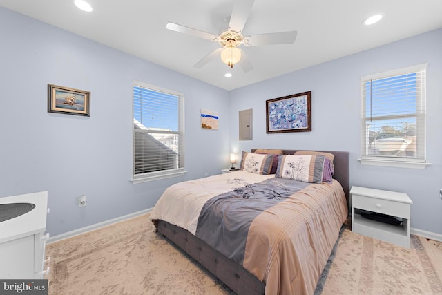 bedroom with multiple windows, ceiling fan, and electric panel