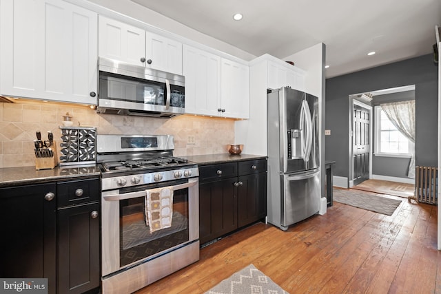 kitchen with appliances with stainless steel finishes, light hardwood / wood-style floors, white cabinetry, and tasteful backsplash