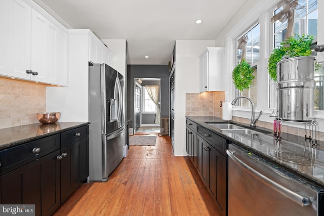 kitchen with white cabinets, stainless steel appliances, dark stone countertops, and tasteful backsplash