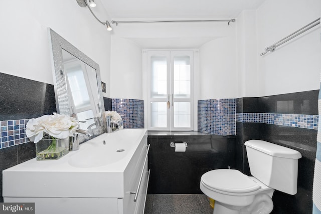 bathroom with tile walls, vanity, and toilet