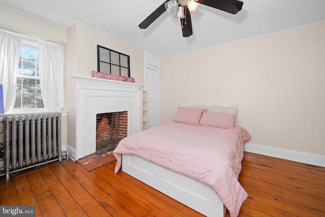 bedroom with wood-type flooring, ceiling fan, and radiator heating unit