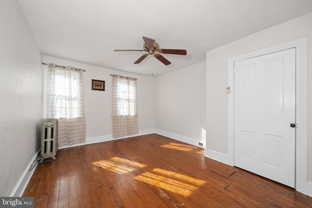 unfurnished room featuring radiator, ceiling fan, and dark hardwood / wood-style floors