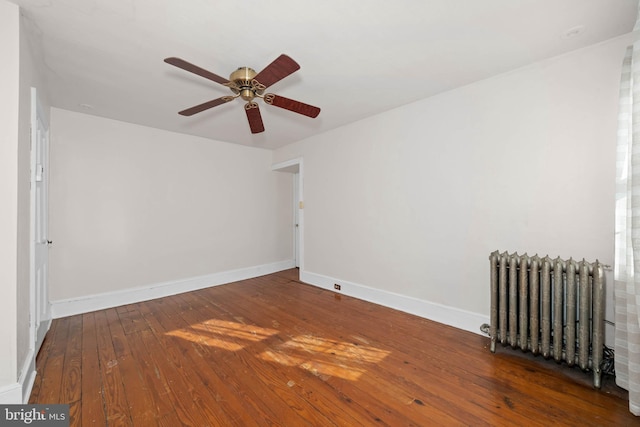 unfurnished room featuring dark wood-type flooring, ceiling fan, and radiator heating unit