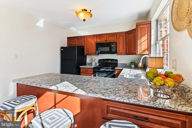 kitchen featuring light stone counters, sink, and black appliances