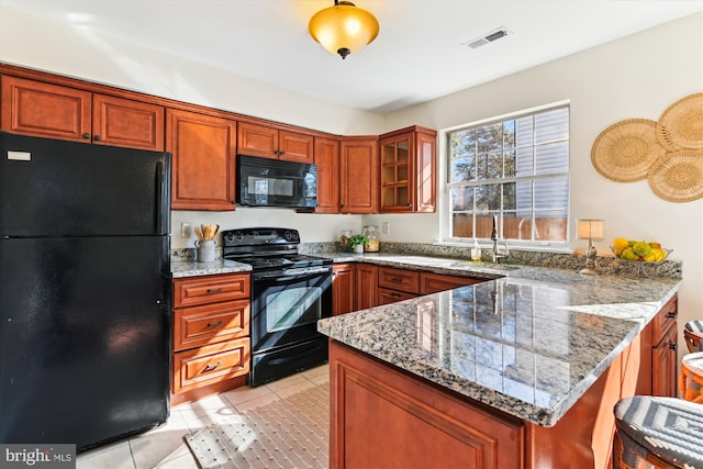 kitchen with black appliances, sink, light tile patterned floors, kitchen peninsula, and light stone countertops