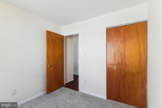 unfurnished bedroom with dark colored carpet and a closet