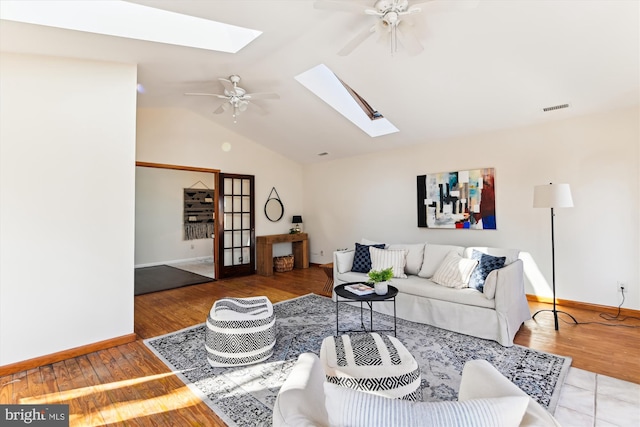 living room featuring ceiling fan, lofted ceiling with skylight, and hardwood / wood-style floors