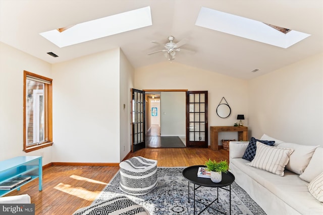 living room featuring wood-type flooring, lofted ceiling with skylight, and ceiling fan