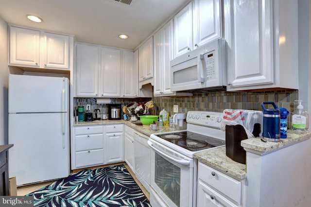 kitchen with light stone countertops, white appliances, white cabinets, and tasteful backsplash