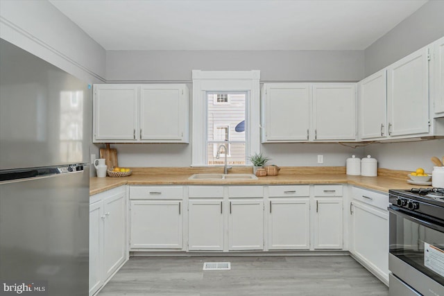 kitchen with sink, stainless steel appliances, light hardwood / wood-style flooring, and white cabinets