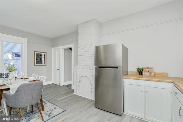 kitchen featuring white cabinets, light wood-type flooring, and stainless steel fridge