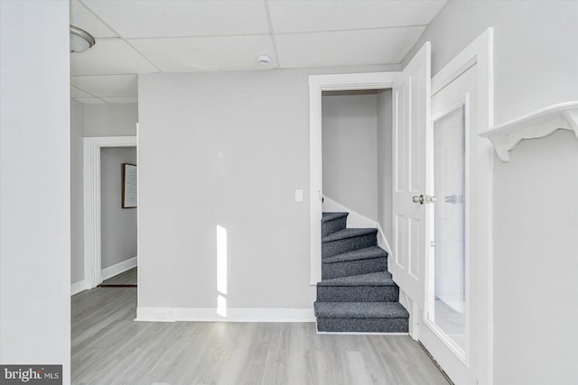 staircase with wood-type flooring and a paneled ceiling