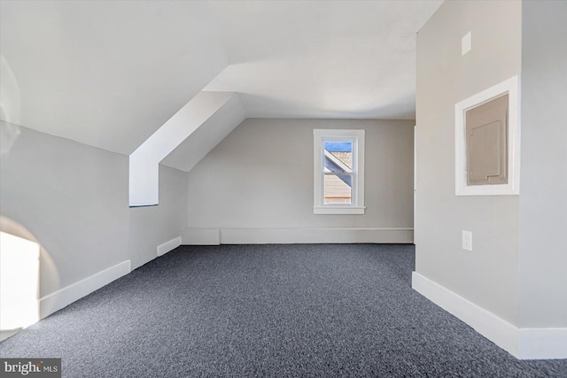 bonus room with lofted ceiling and dark colored carpet