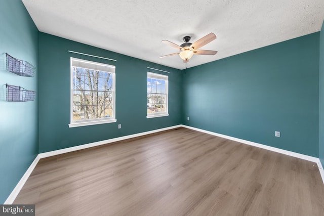 empty room with ceiling fan, hardwood / wood-style floors, and a textured ceiling