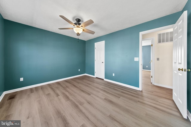 unfurnished bedroom featuring ceiling fan, light hardwood / wood-style floors, and a closet