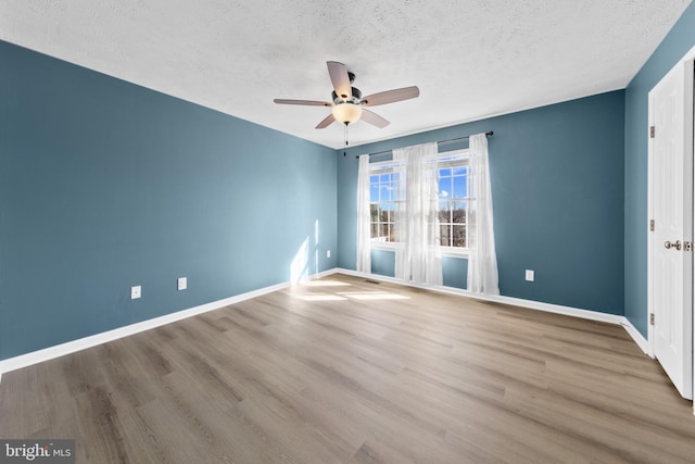 spare room with ceiling fan, a textured ceiling, and light wood-type flooring