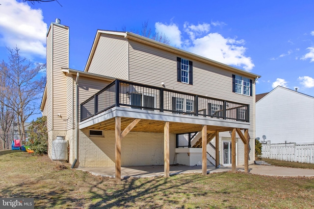 back of property with a patio, a wooden deck, and a lawn