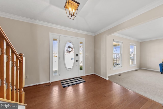 entrance foyer featuring hardwood / wood-style floors, crown molding, and a chandelier