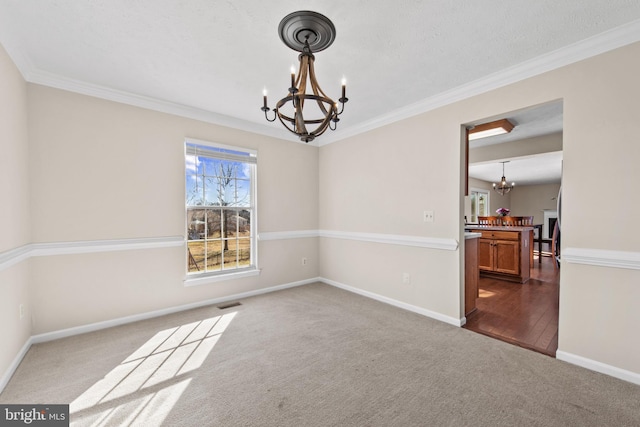 carpeted spare room featuring ornamental molding and a notable chandelier