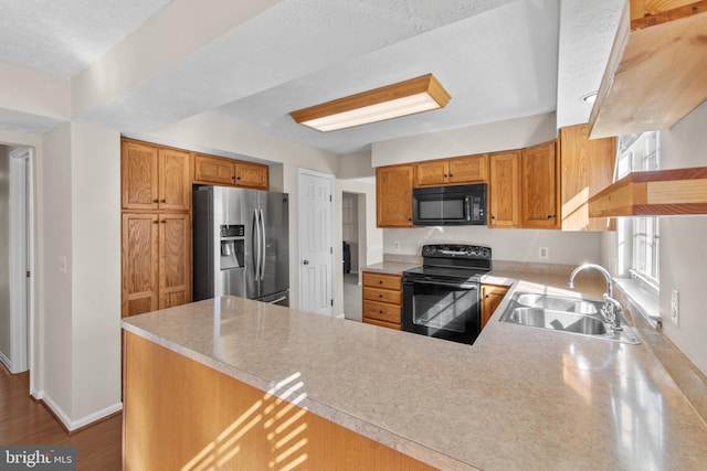 kitchen with hardwood / wood-style flooring, sink, kitchen peninsula, and black appliances