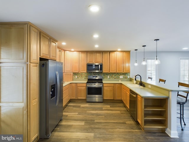 kitchen with kitchen peninsula, a breakfast bar area, stainless steel appliances, decorative light fixtures, and sink