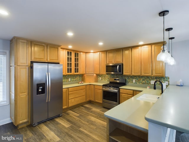 kitchen featuring kitchen peninsula, stainless steel appliances, dark hardwood / wood-style floors, hanging light fixtures, and sink