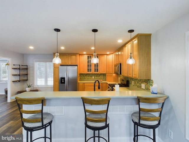 kitchen featuring backsplash, appliances with stainless steel finishes, a kitchen breakfast bar, and dark hardwood / wood-style flooring