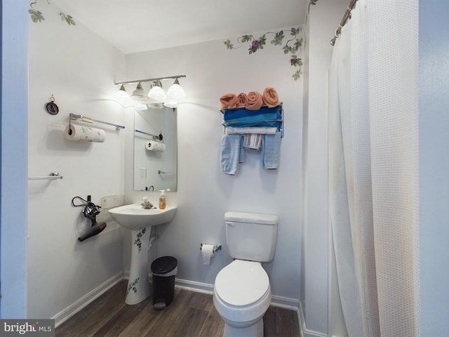 bathroom with toilet, hardwood / wood-style flooring, and curtained shower