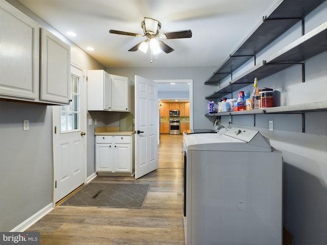 clothes washing area with cabinets, separate washer and dryer, light hardwood / wood-style flooring, and ceiling fan