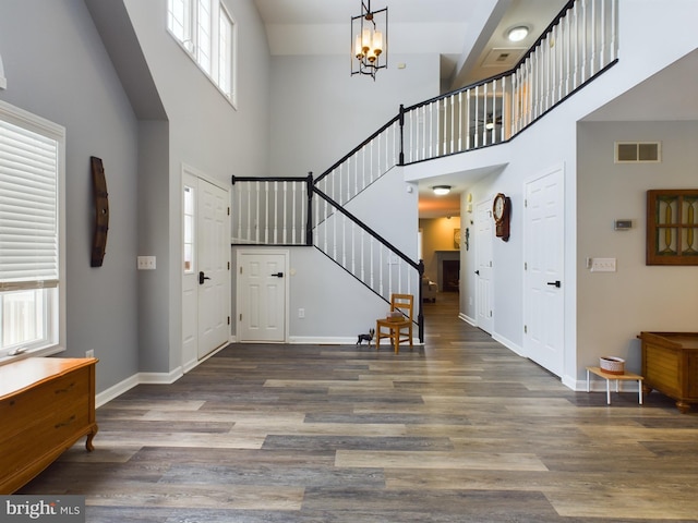 entryway featuring a towering ceiling, a wealth of natural light, a chandelier, and dark hardwood / wood-style floors