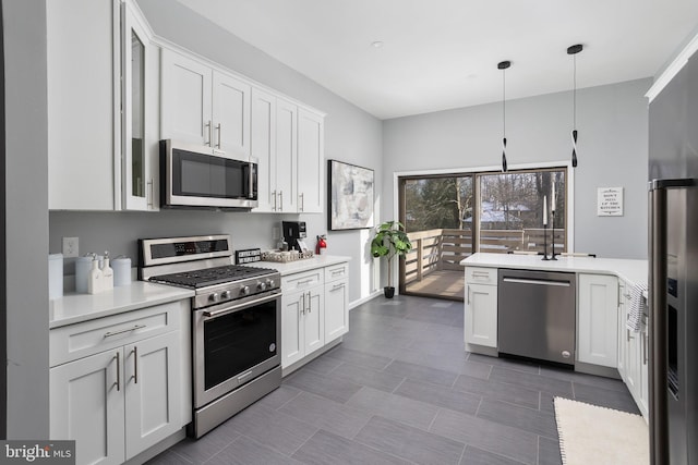 kitchen featuring stainless steel appliances, pendant lighting, and white cabinets