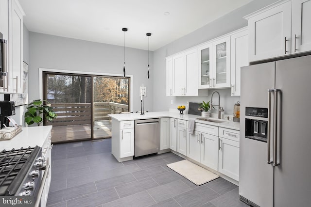 kitchen featuring appliances with stainless steel finishes, white cabinets, kitchen peninsula, and hanging light fixtures