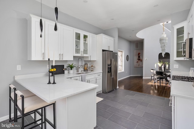 kitchen featuring kitchen peninsula, high end fridge, pendant lighting, white cabinets, and sink