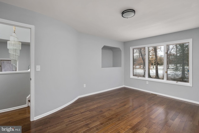 unfurnished room featuring dark hardwood / wood-style floors and a chandelier