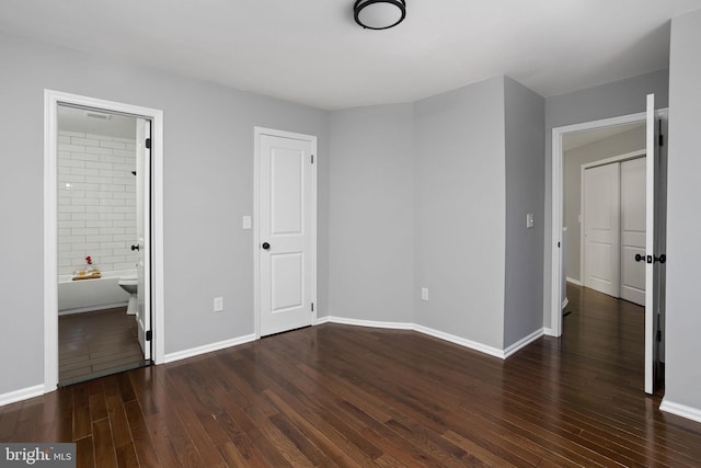 unfurnished bedroom with dark wood-type flooring and connected bathroom